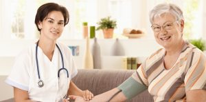 Nurse measuring blood pressure of senior woman at home. Looking home care insurance